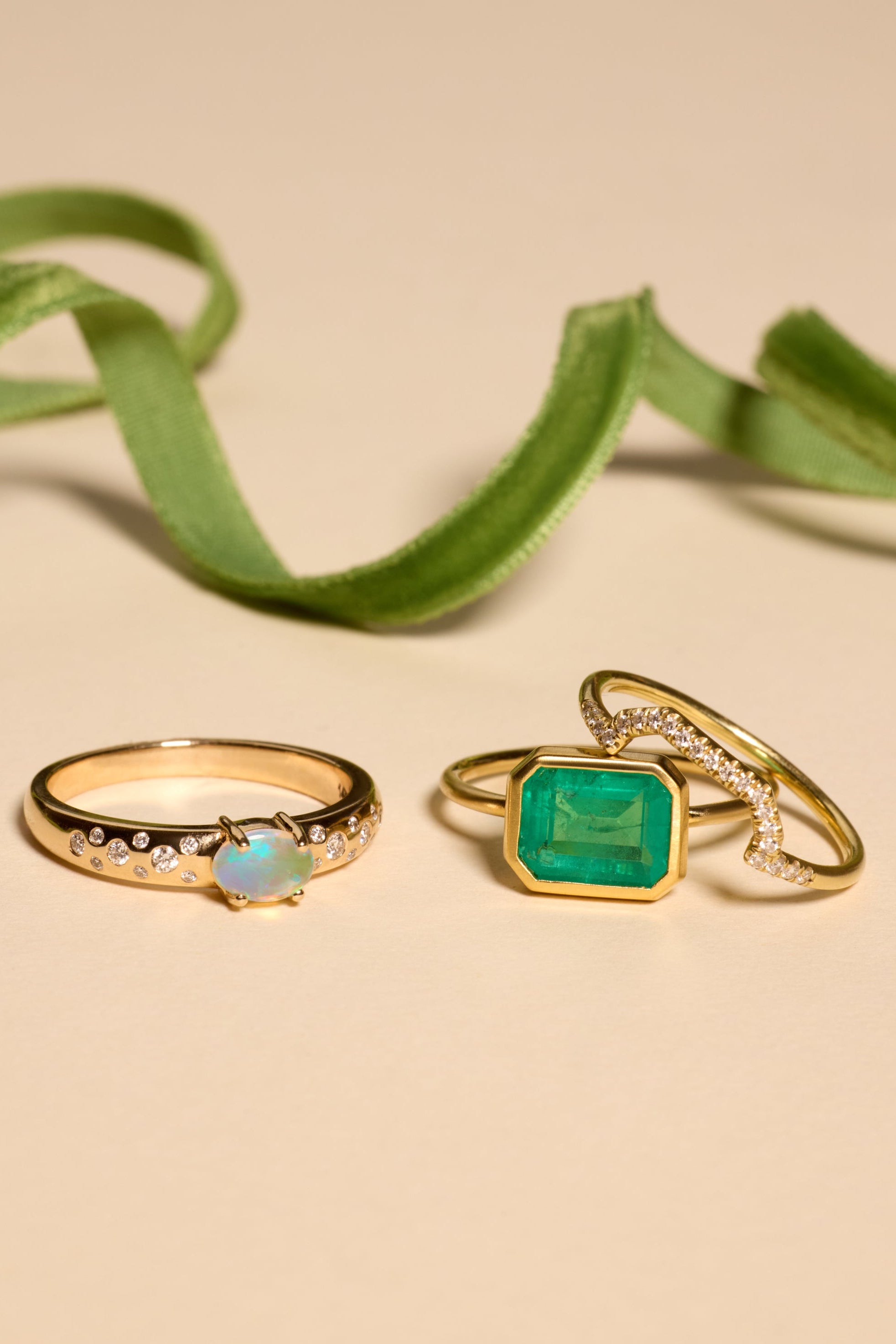 Two gold rings with gemstones on a beige background