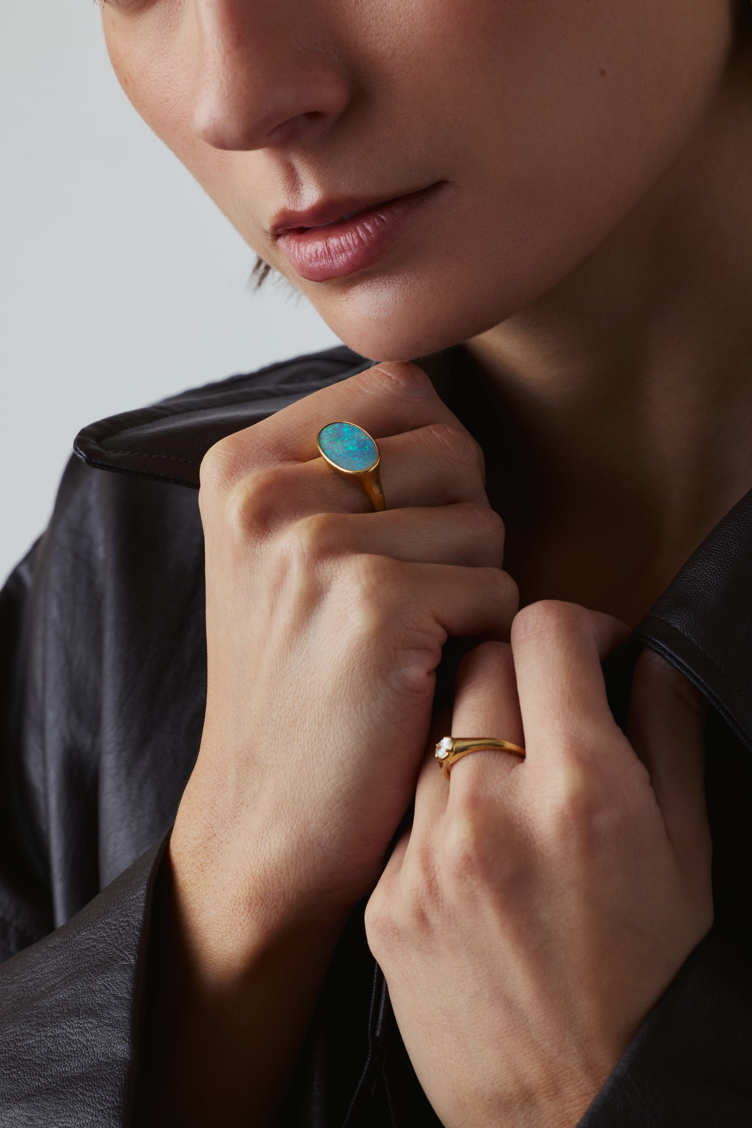 Close-up of a person wearing two rings on their fingers against a neutral background