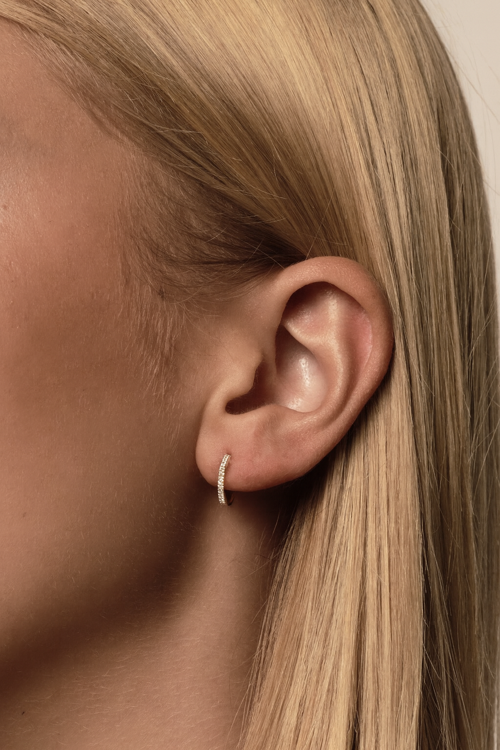 a close up photo of a diamond huggie hoop on a blonde girl